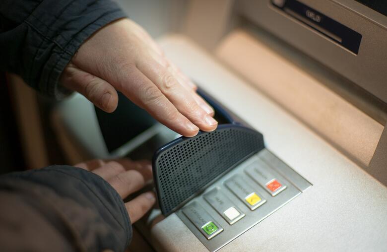 to hender på et minibankdisplay, ene hånden skjuler inntastingen to hender på et minibankdisplay, ene hånden skjuler inntastingen